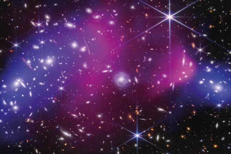 Photo prise dans l'espace. Plusieurs points lumineux blancs, certains avec des halos circulaires ou 6 rayons. Le fond du ciel est noir, rosé ou violacé.